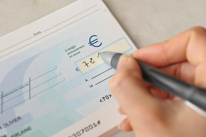 Photo illustrant une personne remplissant un chèque bancaire